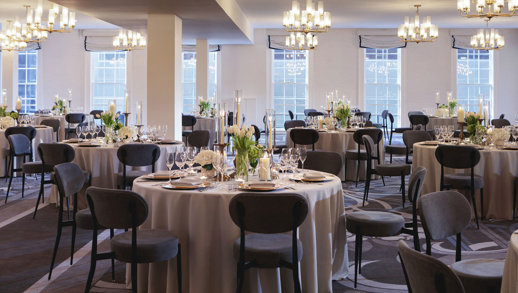 Hotel ballroom set up with tables with floral arrangements and candles