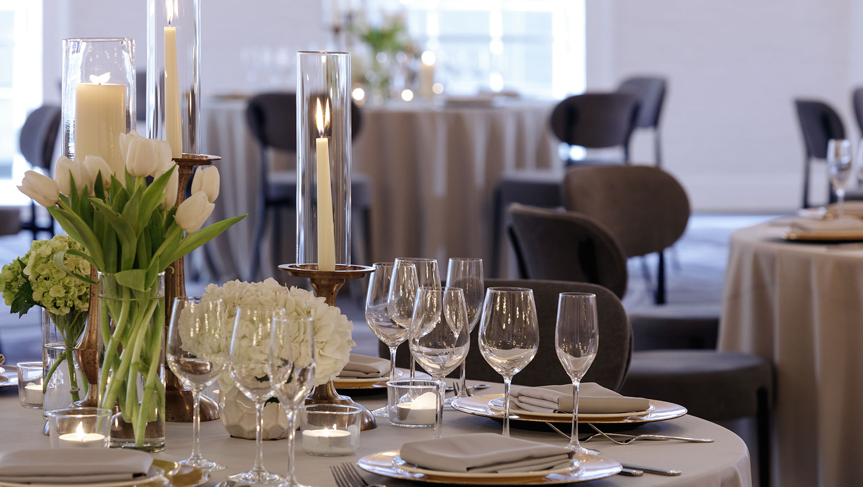 Elegant table setting featuring white tulip florals, candles, and wine glasses