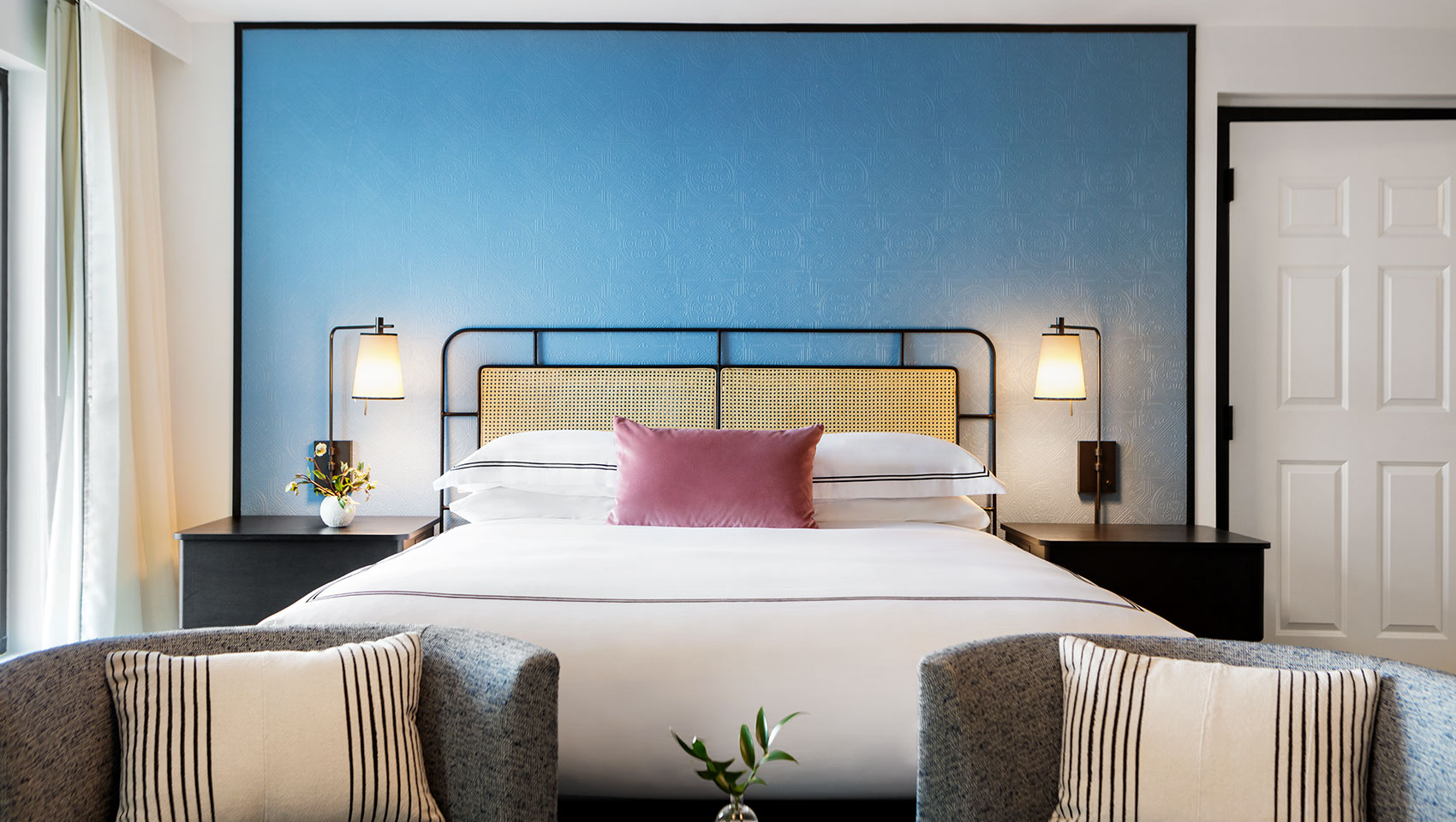 large white king bed with two arm chairs in front of the bed