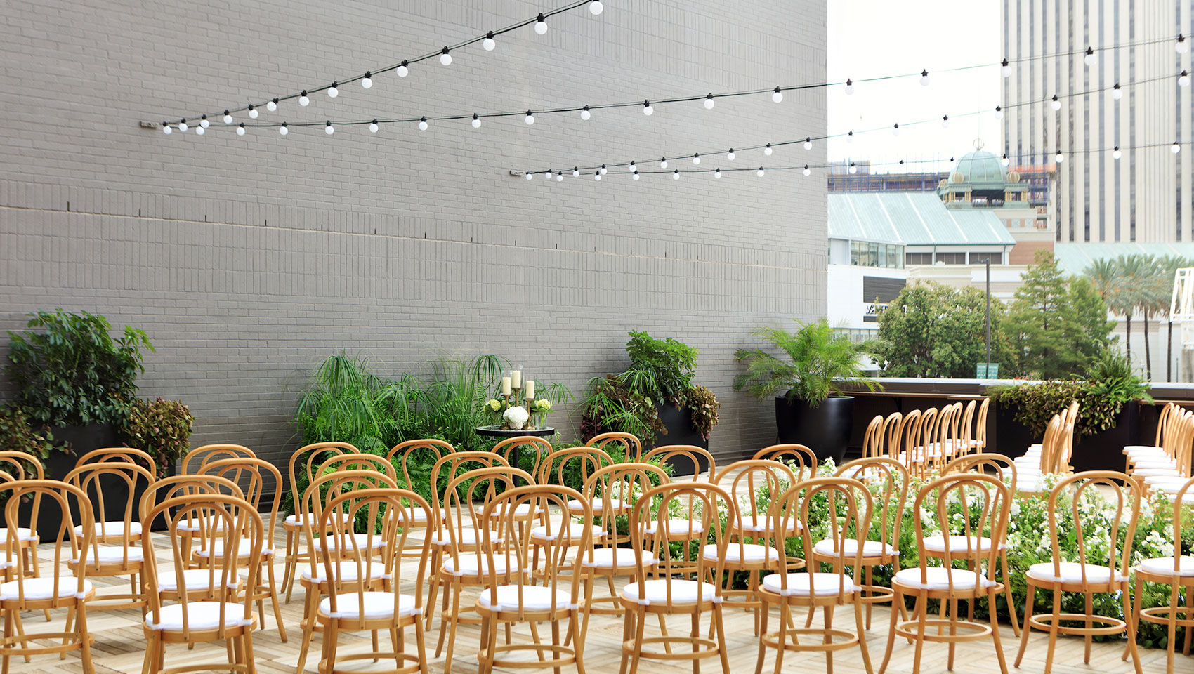 Rooftop wedding ceremony set up with rattan chairs and white florals