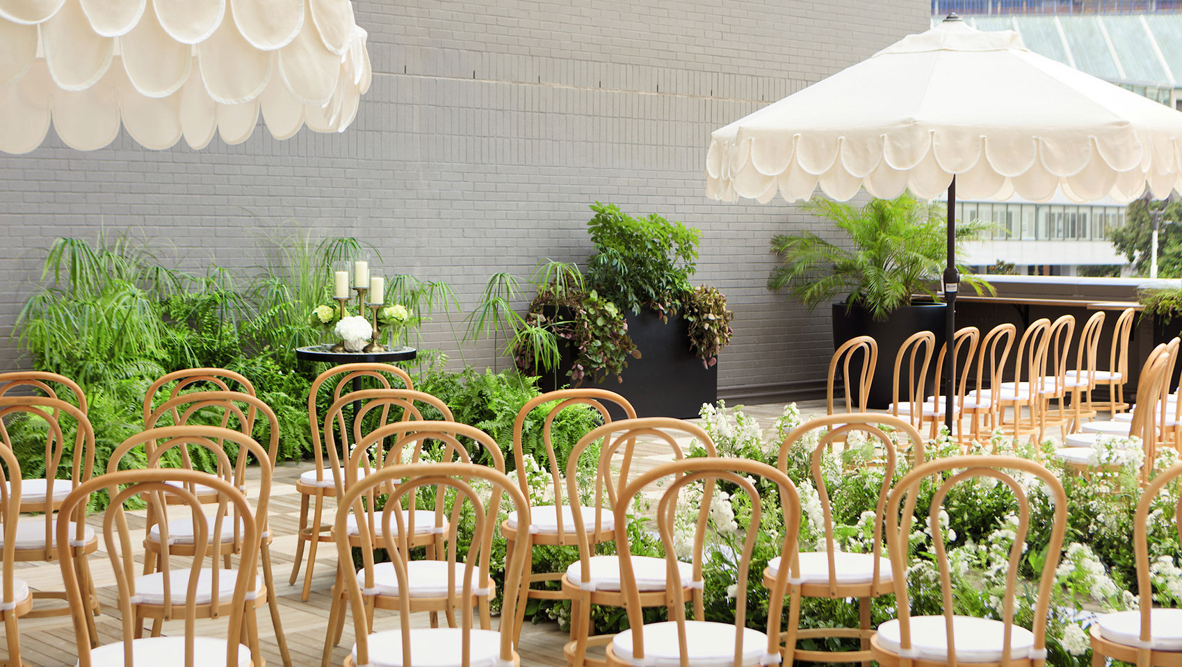 Rooftop wedding ceremony set up with rattan chairs, white florals and white