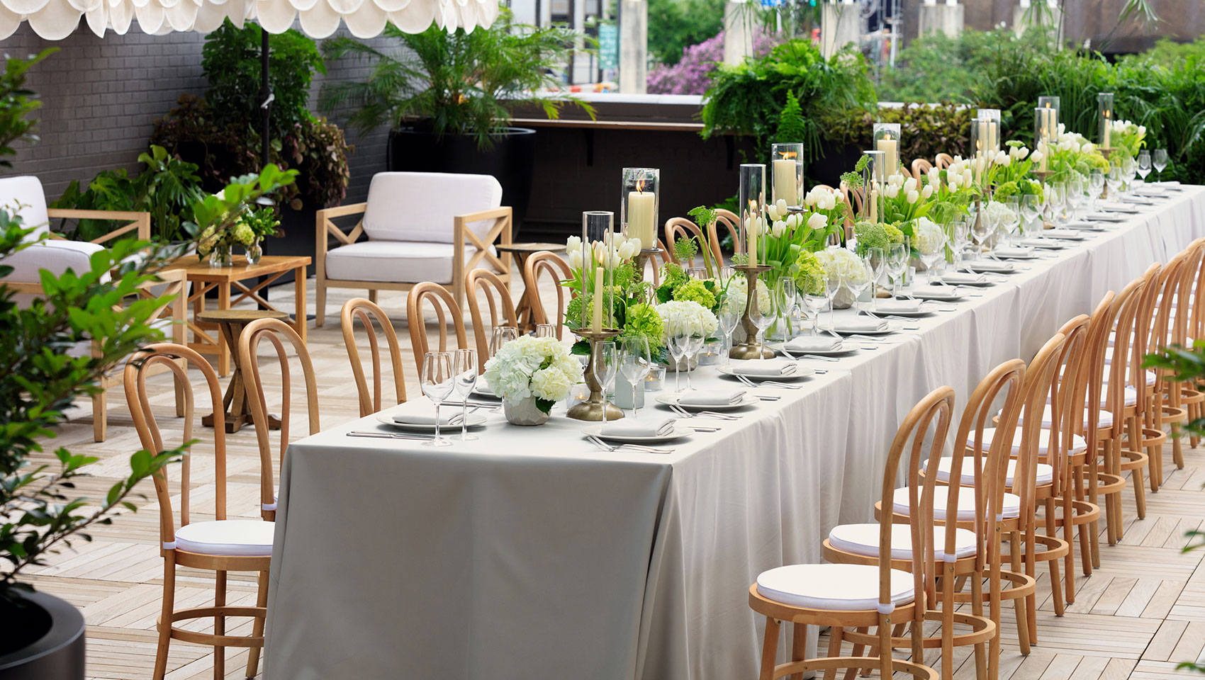 Rooftop wedding reception set up with a long table, white florals, and place settings