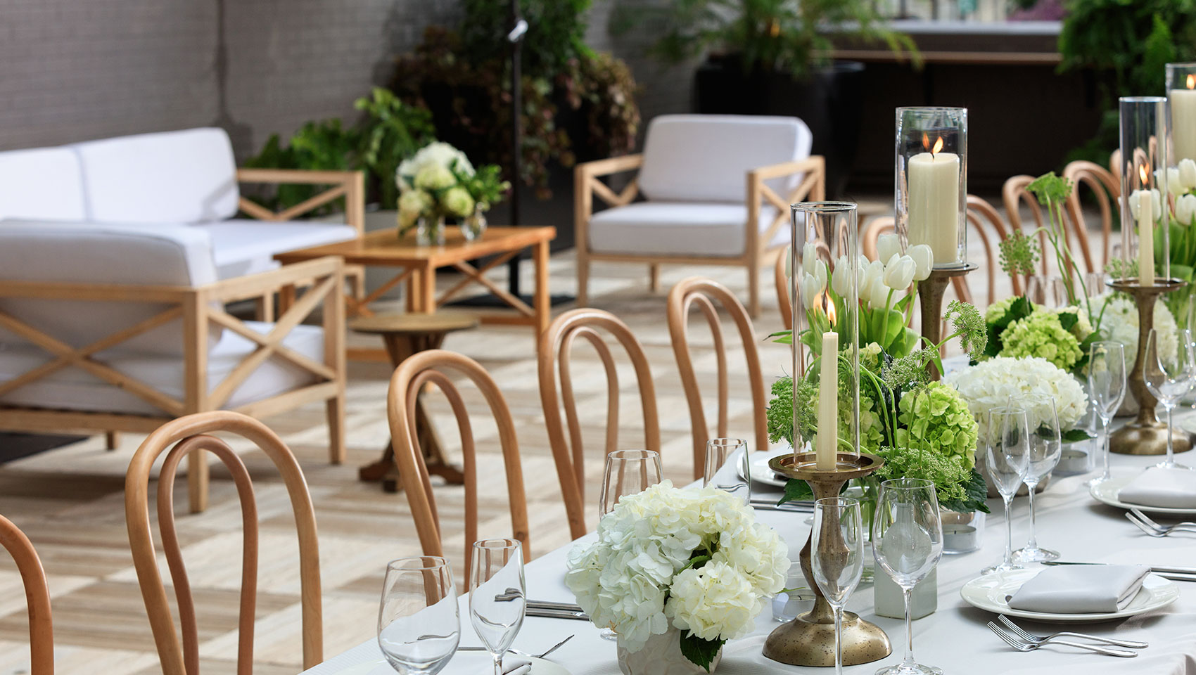 Rooftop wedding reception set up with a long table, white florals, and place settings