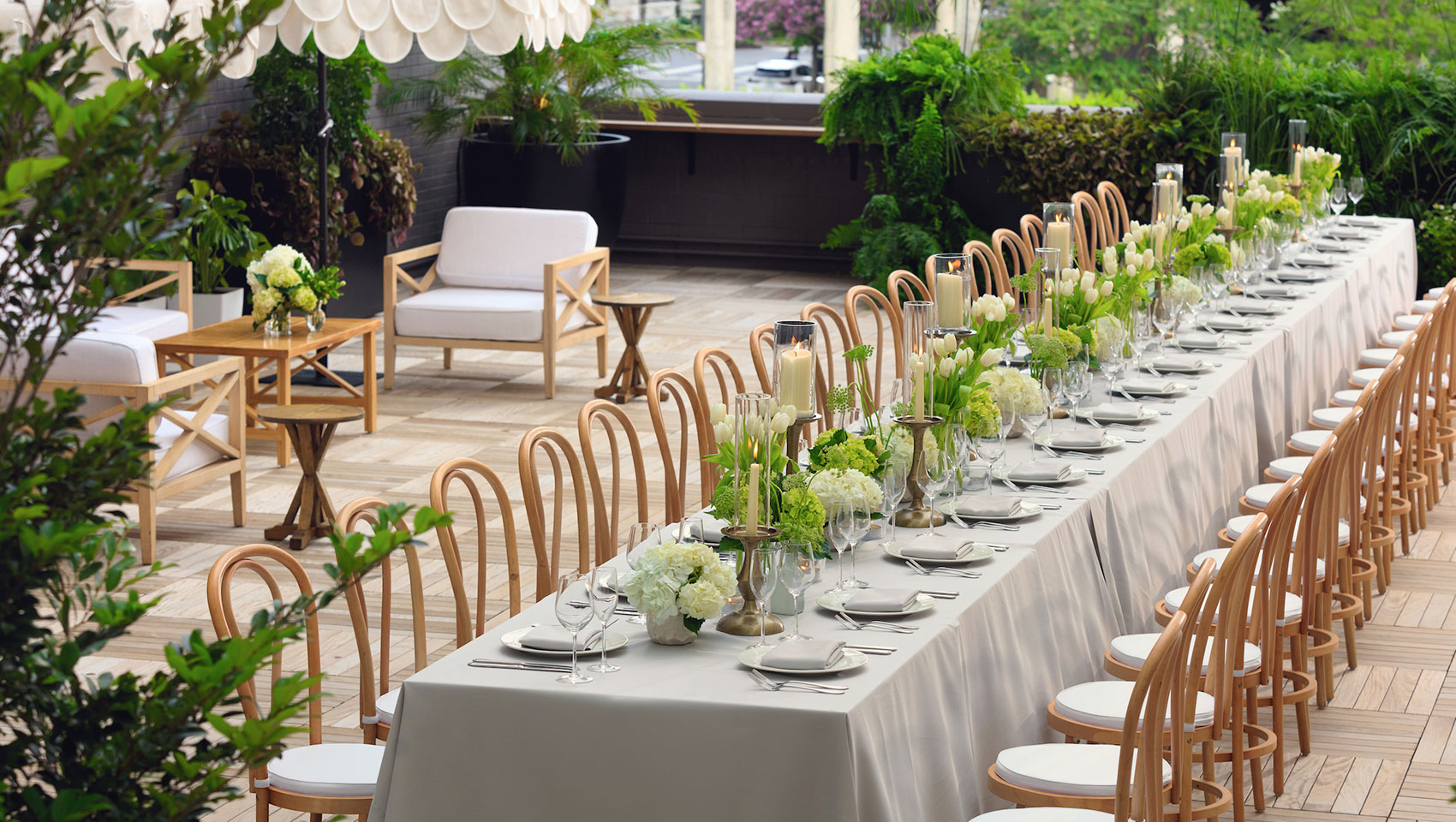 Rooftop wedding reception set up with a long table, white florals, and place settings