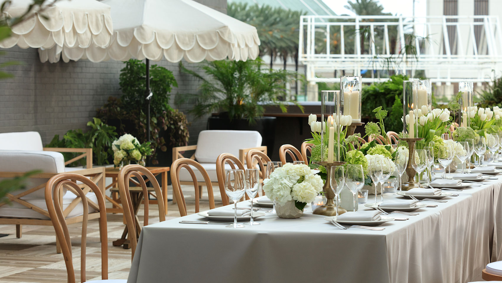 Rooftop wedding reception set up with a long table, white florals, and place settings