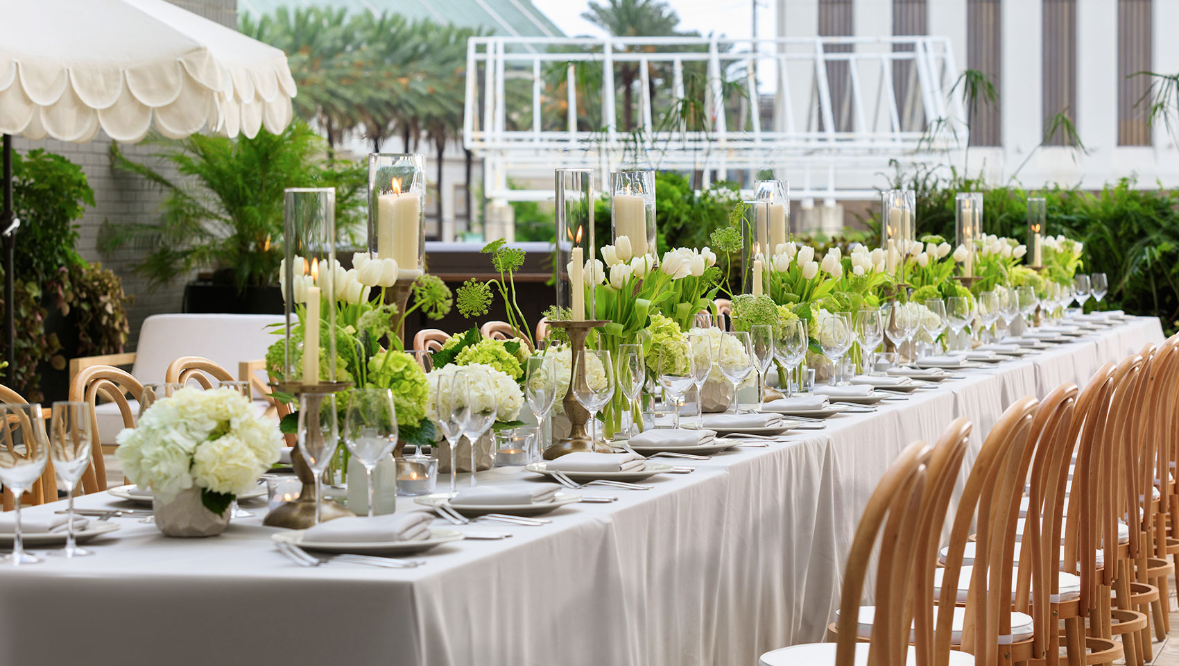 Rooftop wedding reception set up with a long table, white florals, and place settings