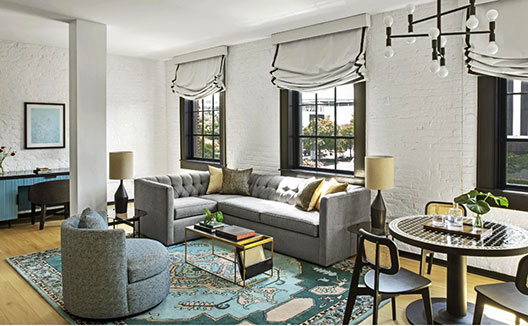 The Fiddle Suite at Hotel Fontenot image shows a plush king bed and a settee with a desk and chair